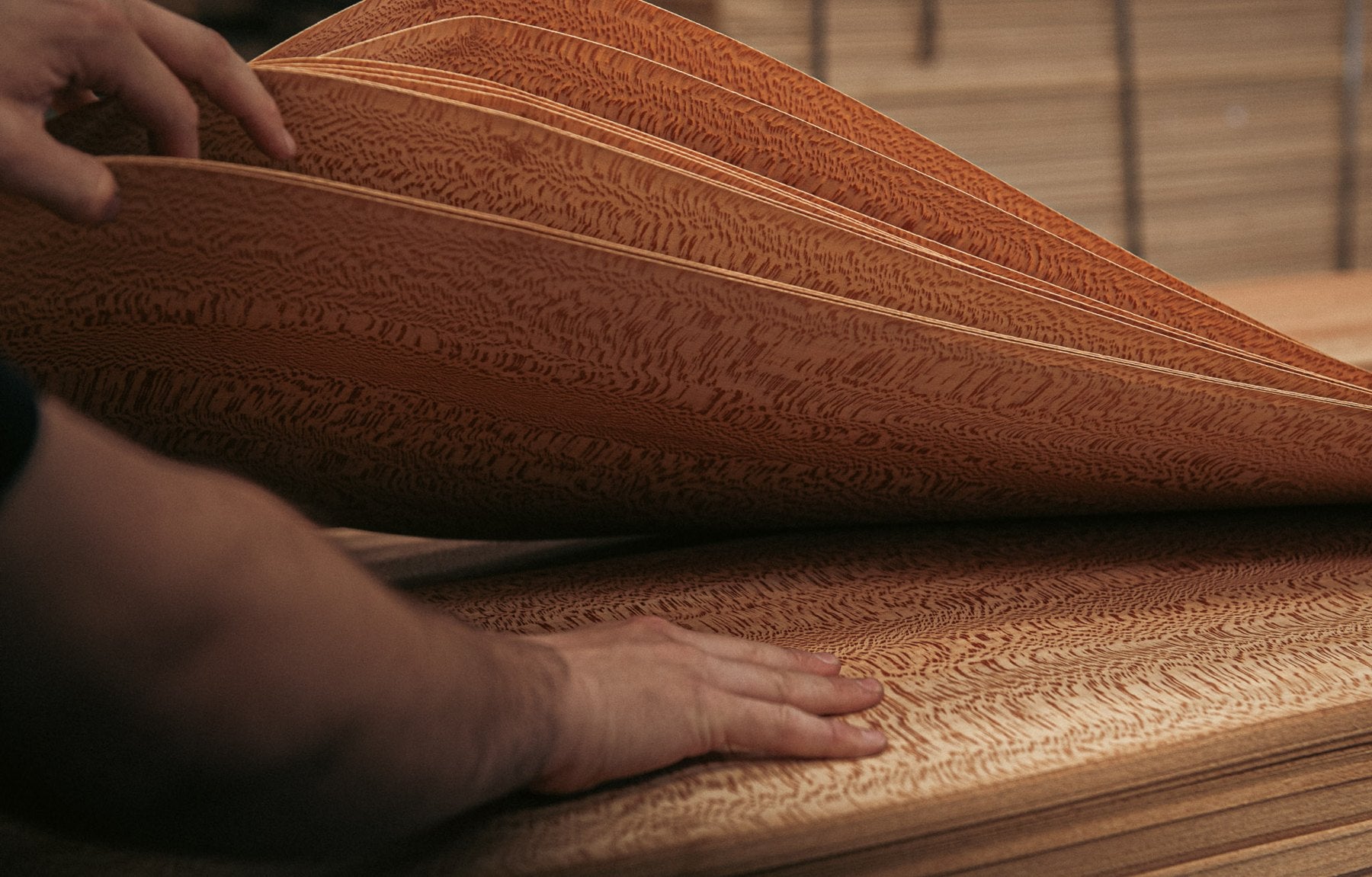 Hands separating figured wood veneer leaves